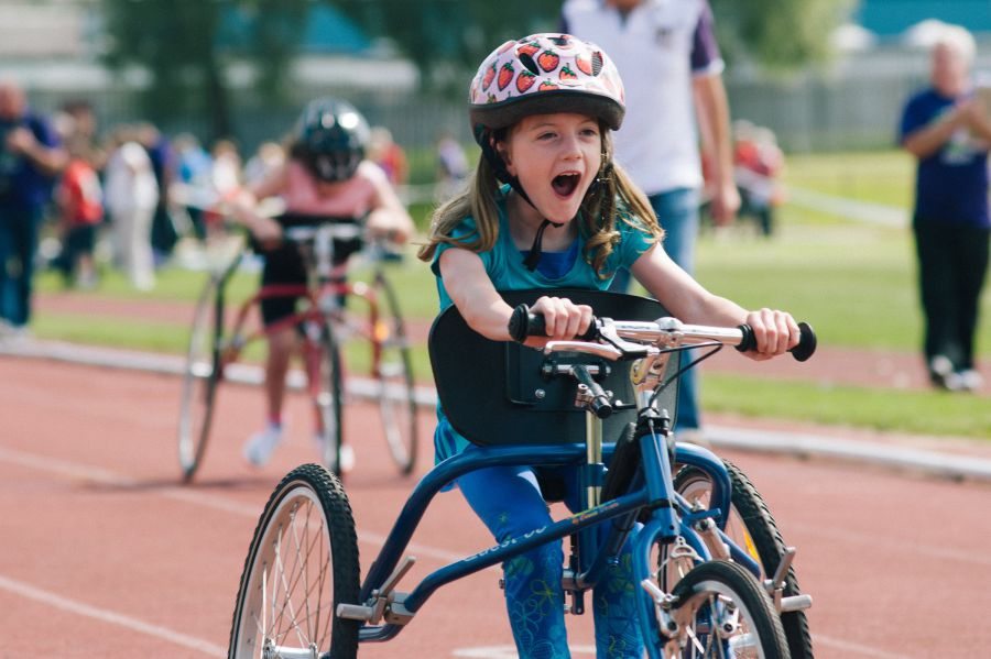 young girl in a frame running bike with a helmet on.